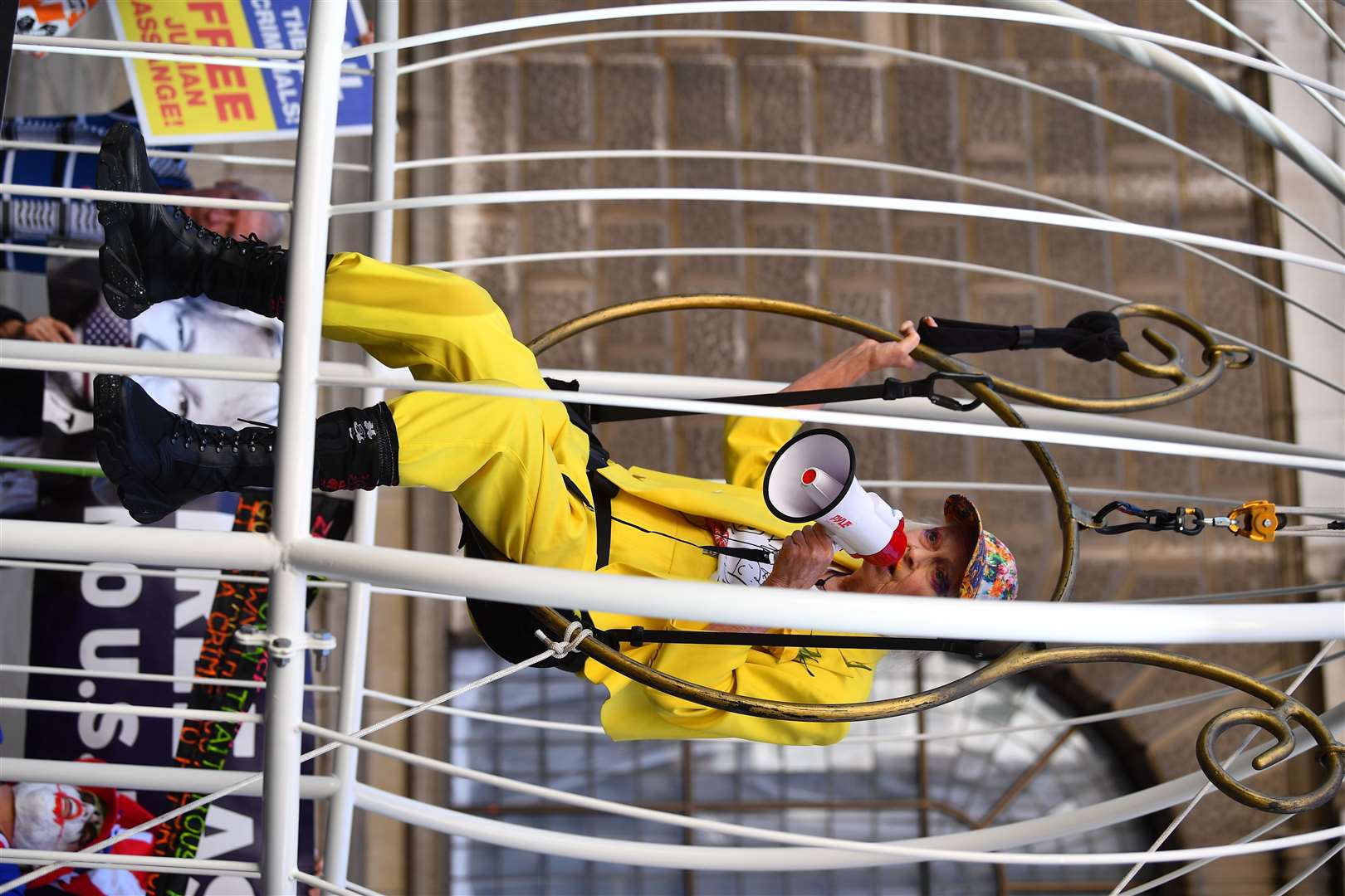 Fashion designer and businesswoman Dame Vivienne Westwood is suspended in a 10ft high bird cage outside the Old Bailey in protest against the US extradition of Julian Assange (Victoria Jones/PA)