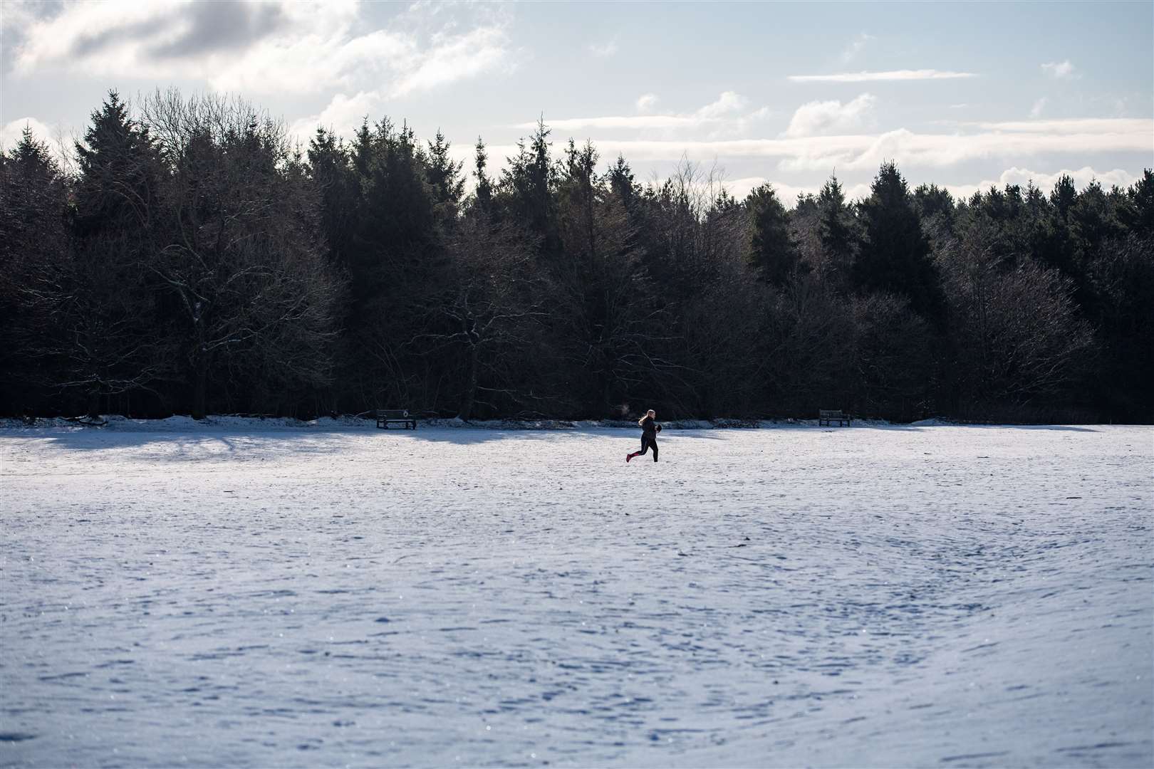 A runner navigates snow and ice at Lickey Hills Country Park in Birmingham (Jacob King/PA)