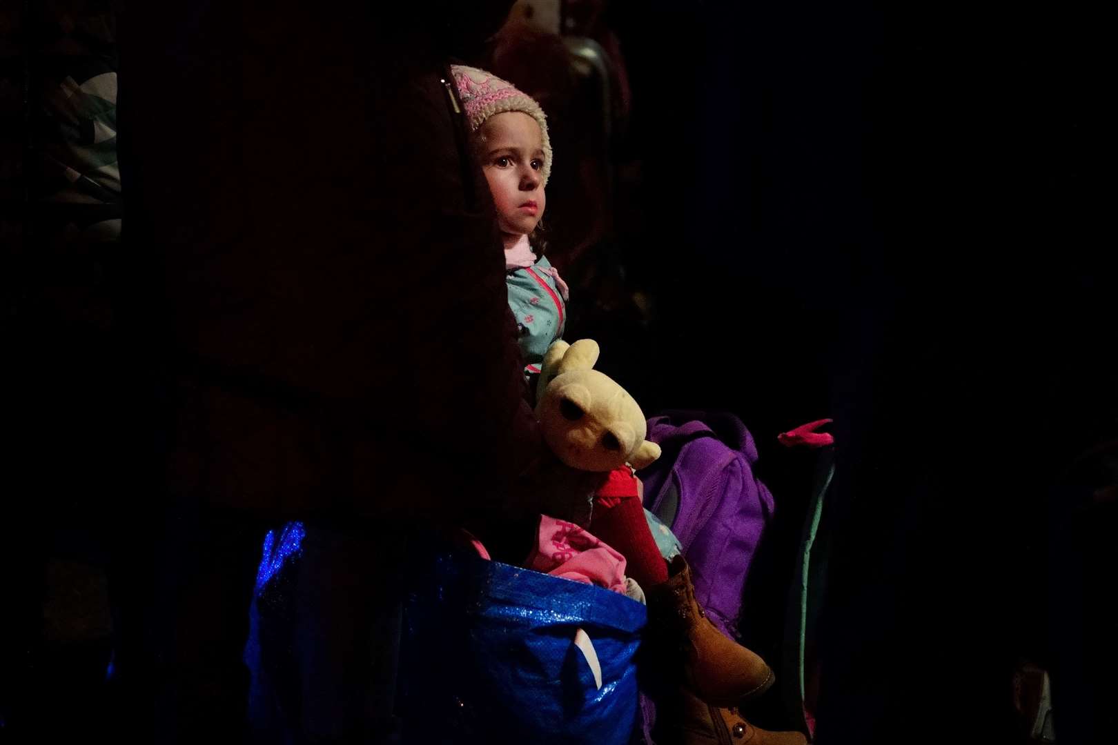 A young girl from Ukraine sits on a suitcase outside Przemysl Glowny train station in east Poland (Victoria Jones/PA)