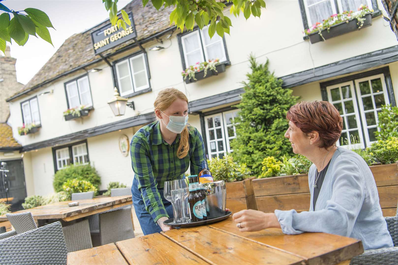 A member of staff wearing PPE serves a customer in the garden of Greene King’s Fort Saint George pub in Cambridge (Adam Smyth/Greene King/PA)