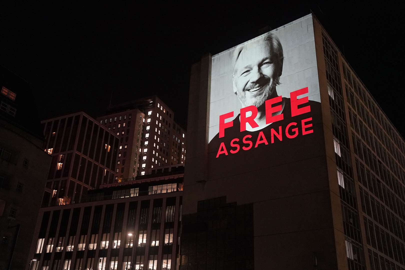 An image of Julian Assange is projected onto a building in Leake Street in central London to mark three years since his arrest and detention in Belmarsh prison while the United States continues with legal moves to extradite him (Victoria Jones/PA)