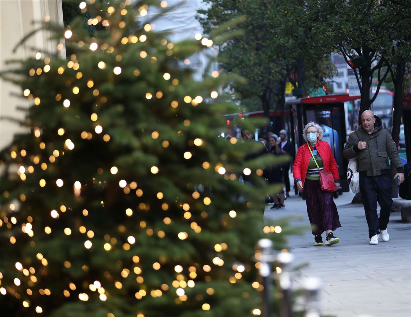 People walk past a Christmas tree outside a store on Oxford Street, central London, before the new national lockdown comes into force in England (Yui Mok/PA)