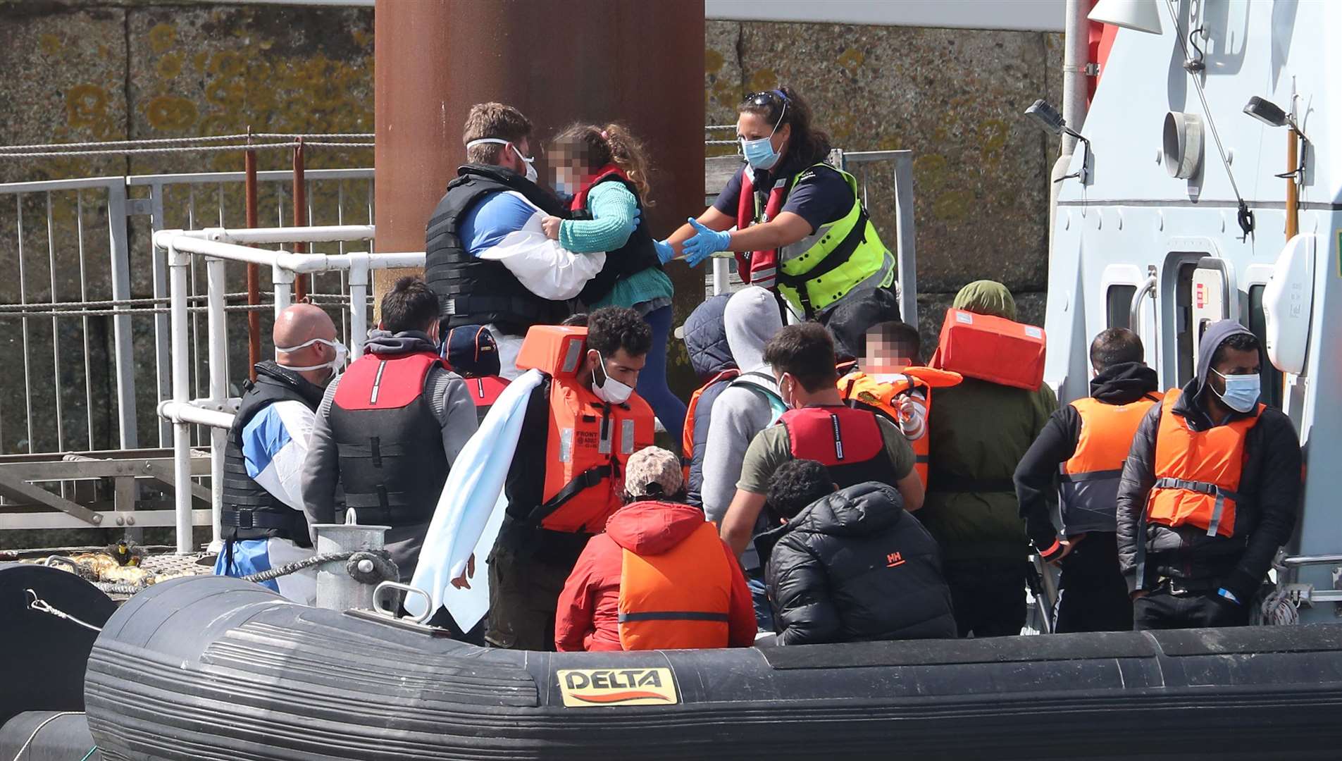 A young girl is carried by a Border Force officer as a group of suspected migrants are brought into Dover (Gareth Fuller/PA)