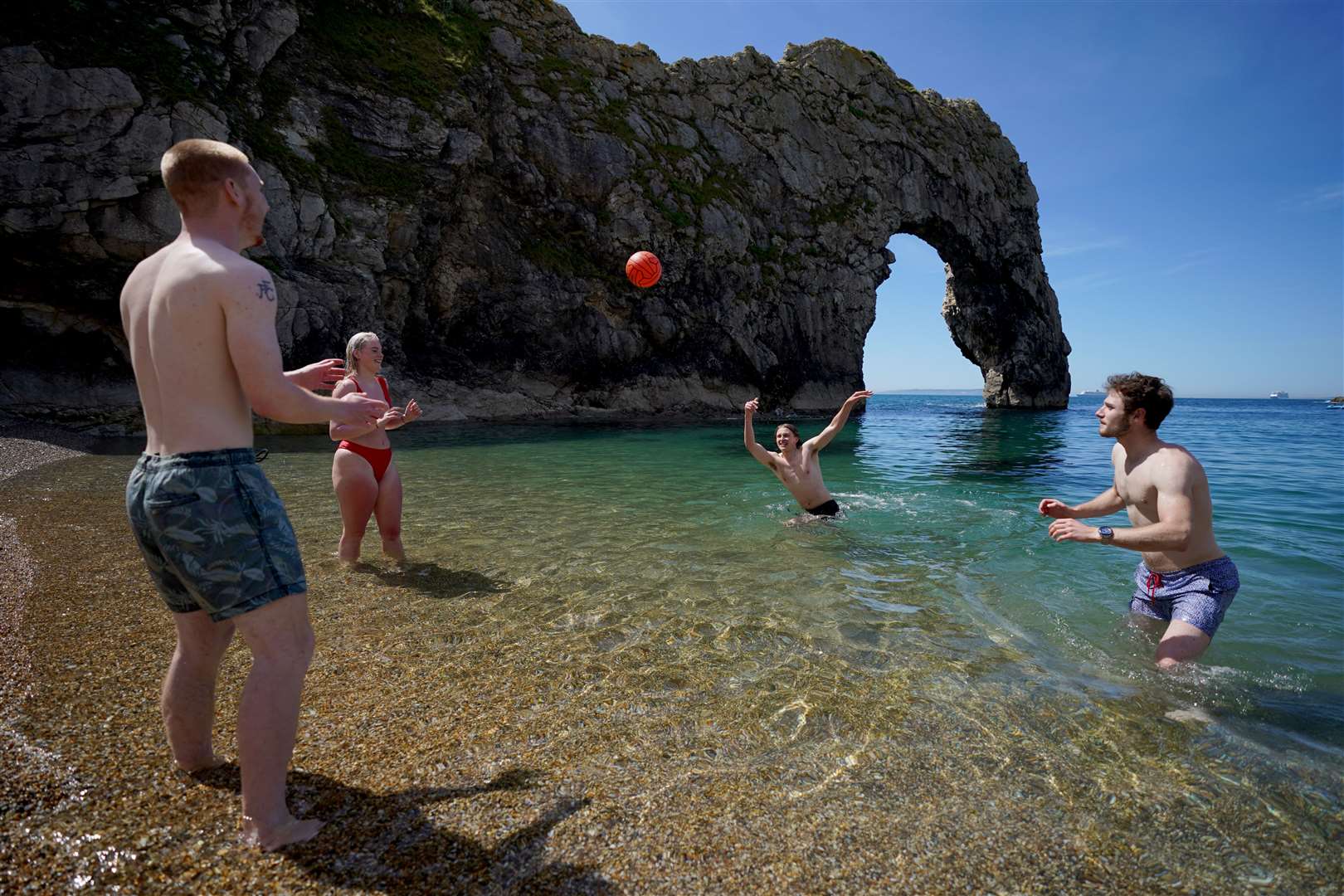 Friends play volleyball in the sea at Durdle Door (Andrew Matthews/PA)