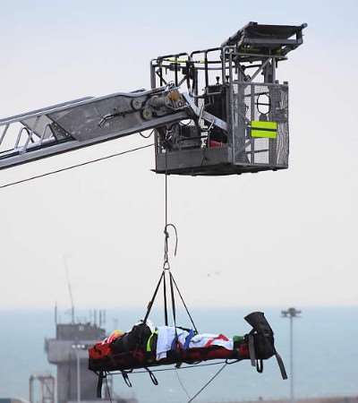 Firefighters winch the man to safety after he fell down the cliff next to a road.