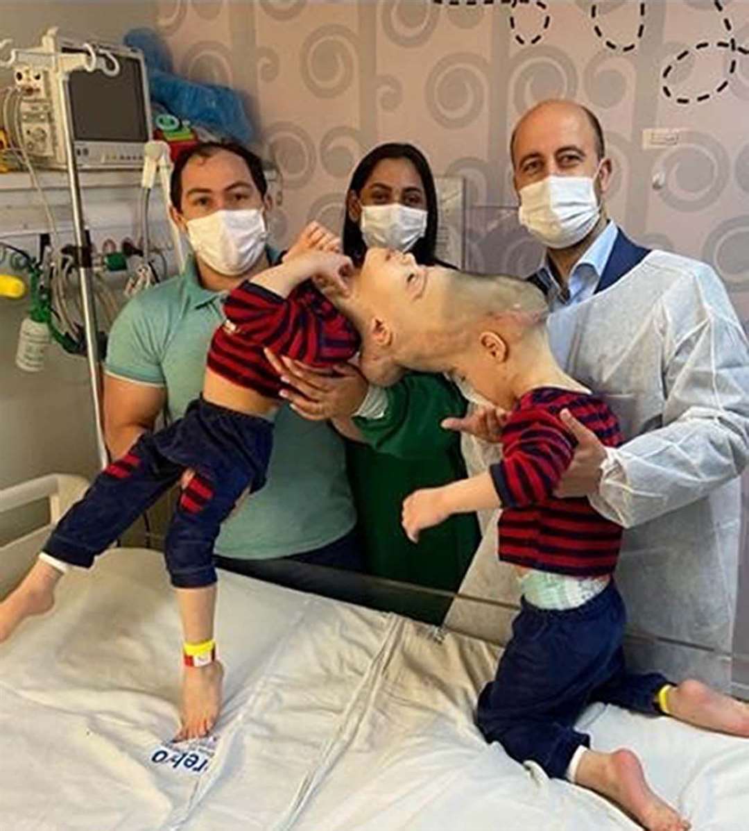 Surgeon Noor ul Owase Jeelani with Bernardo (left) and Arthur, and their parents, Adriely and Antonia Lima (Gemini Untwined/PA)