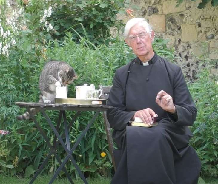 Tiger the cat steals the former Dean of Canterbury Robert Willis' milk during morning prayers. Picture: Canterbury Cathedral / YouTube