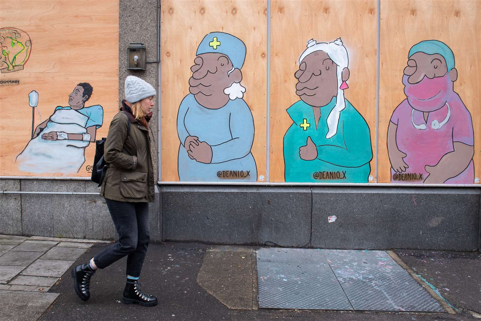 A woman passes a mural showing doctors and nurses in south London (Dominic Lipinski/PA)