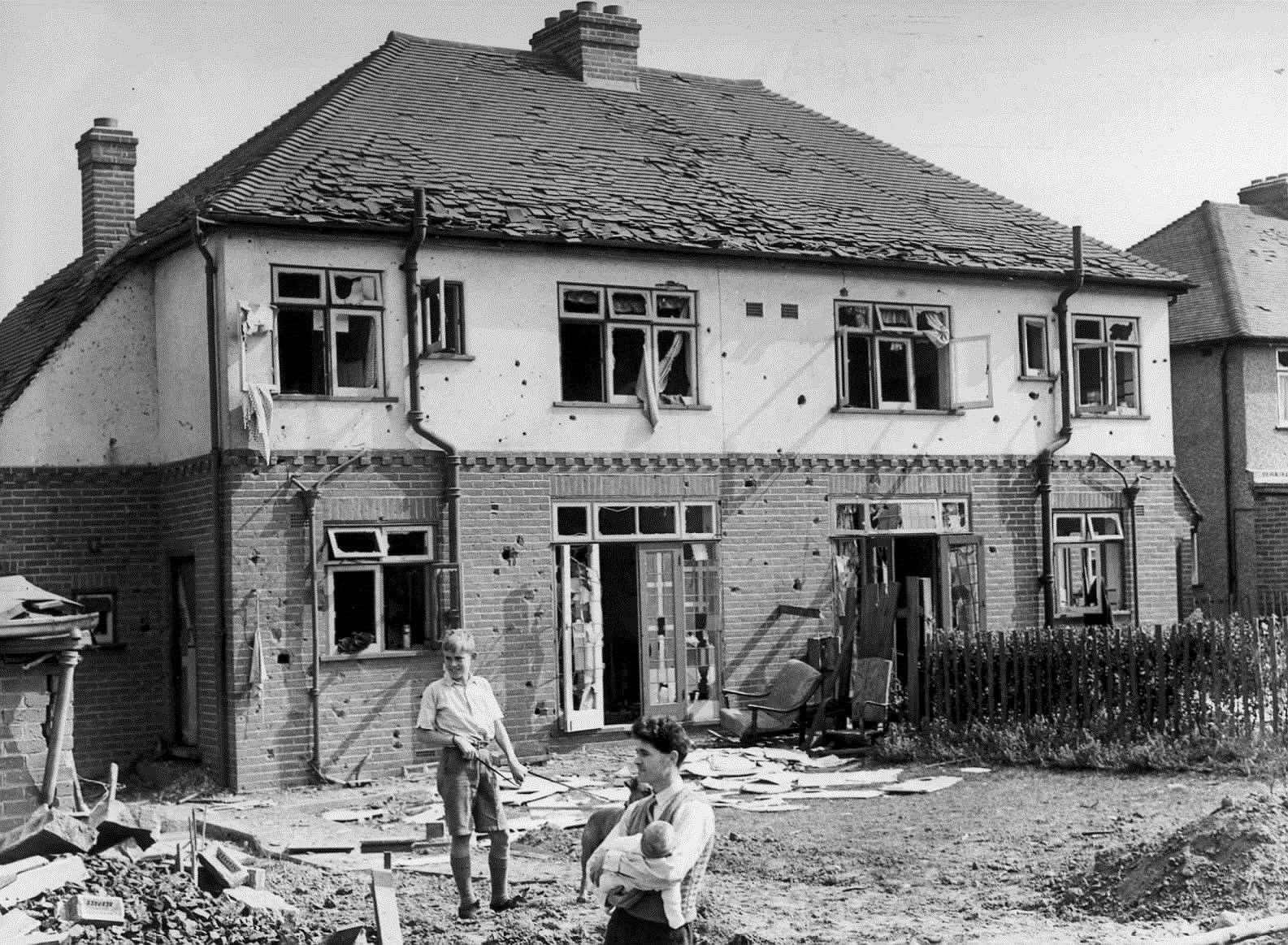 Mr C Beadel with his six-month-old baby in his arms, standing in a crater caused by a bomb which fell in his garden at Wordsworth Road, Maidstone, September, 1940