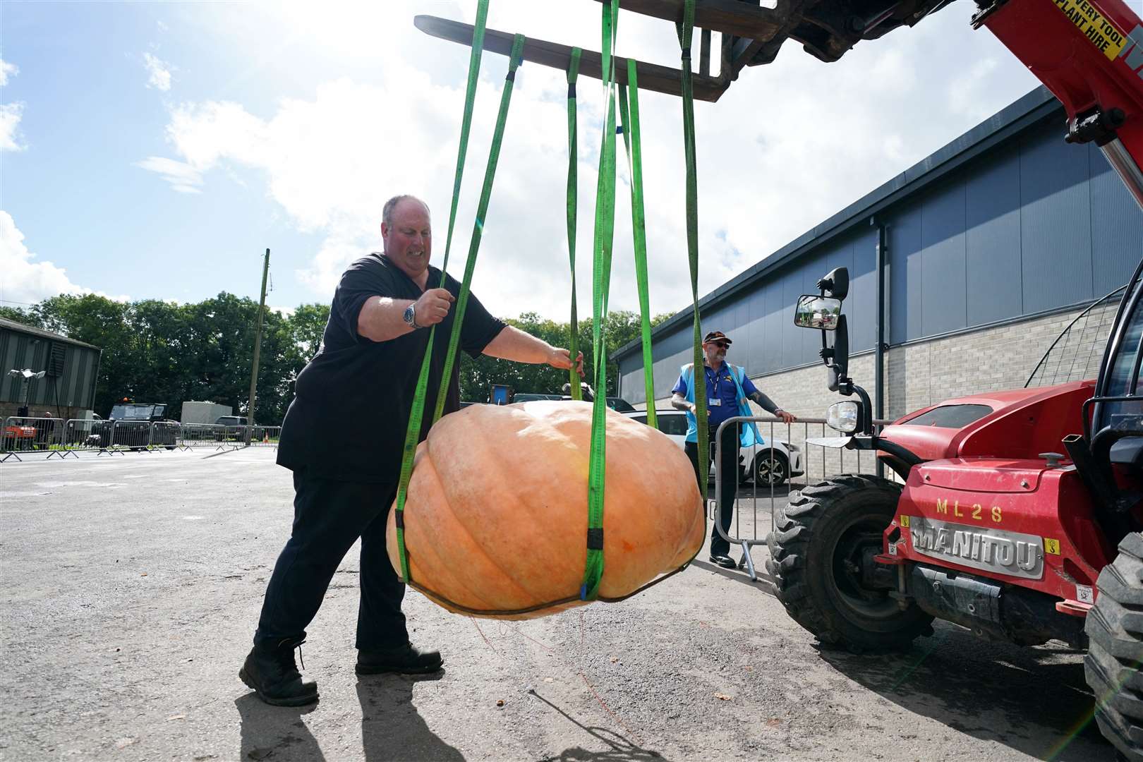 Tim Saint transports a pumpkin he is entering in the UK national giant vegetables championship (Jacob King/PA)