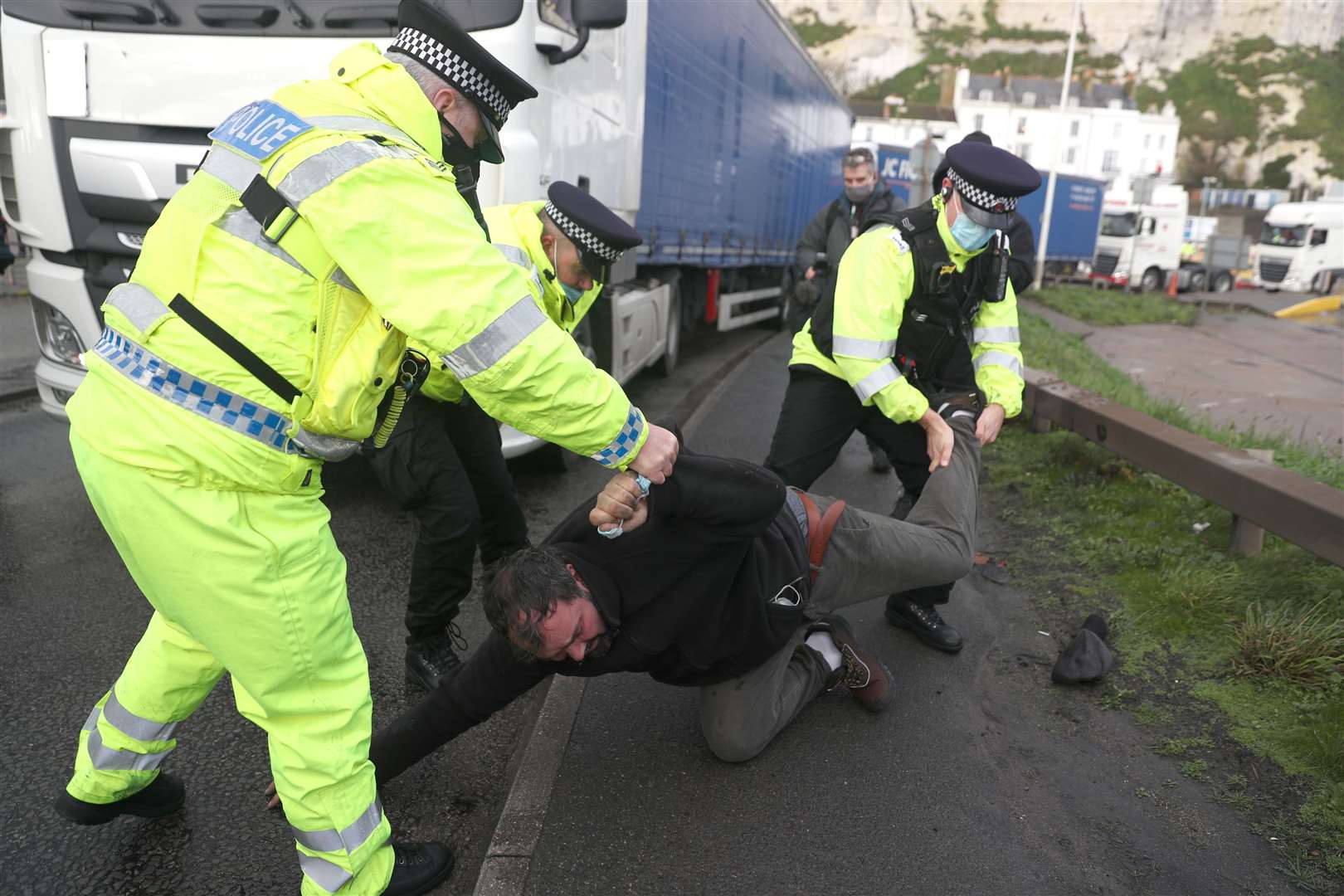 Police remove a man lying in the road in front a freight lorry as it tries to leave the Port of Dover (Andrew Matthews/PA)