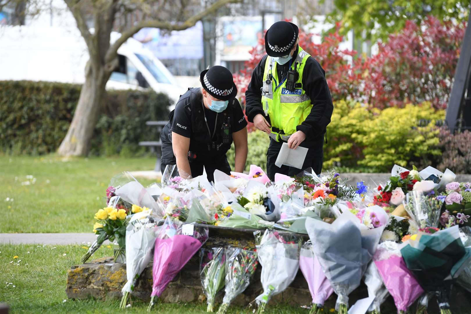 Two police officers lay floral tributes in a park in Aylesham village (Kirsty O’Connor/PA)