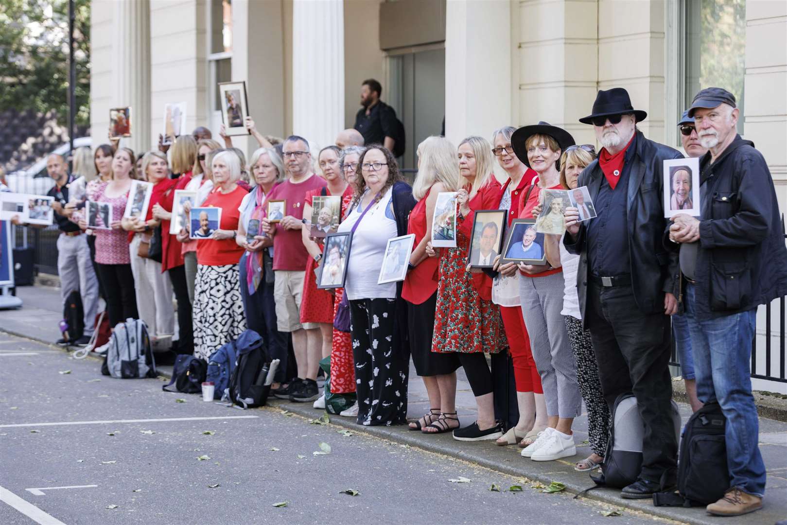 People hold pictures of loved ones lost during the pandemic outside the UK Covid-19 Inquiry at Dorland House in London (Belinda Jiao/PA)