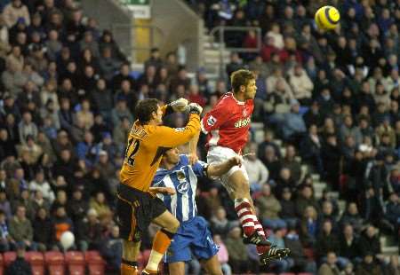 Wigan keeper Mike Pollitt comes through the crowd to punch clear ahead of Hermann Hreidarsson. Picture: ANDY PAYTON