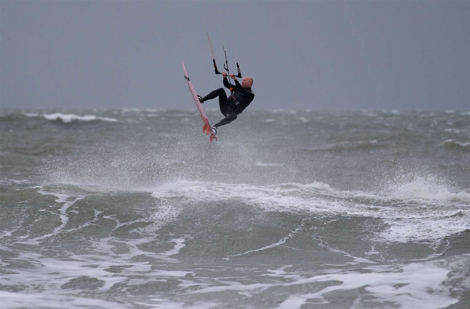 A kite surfer jumps in the air after hitting a wave in the sea off of East Wittering beach in West Sussex (Andrew Matthews/PA)