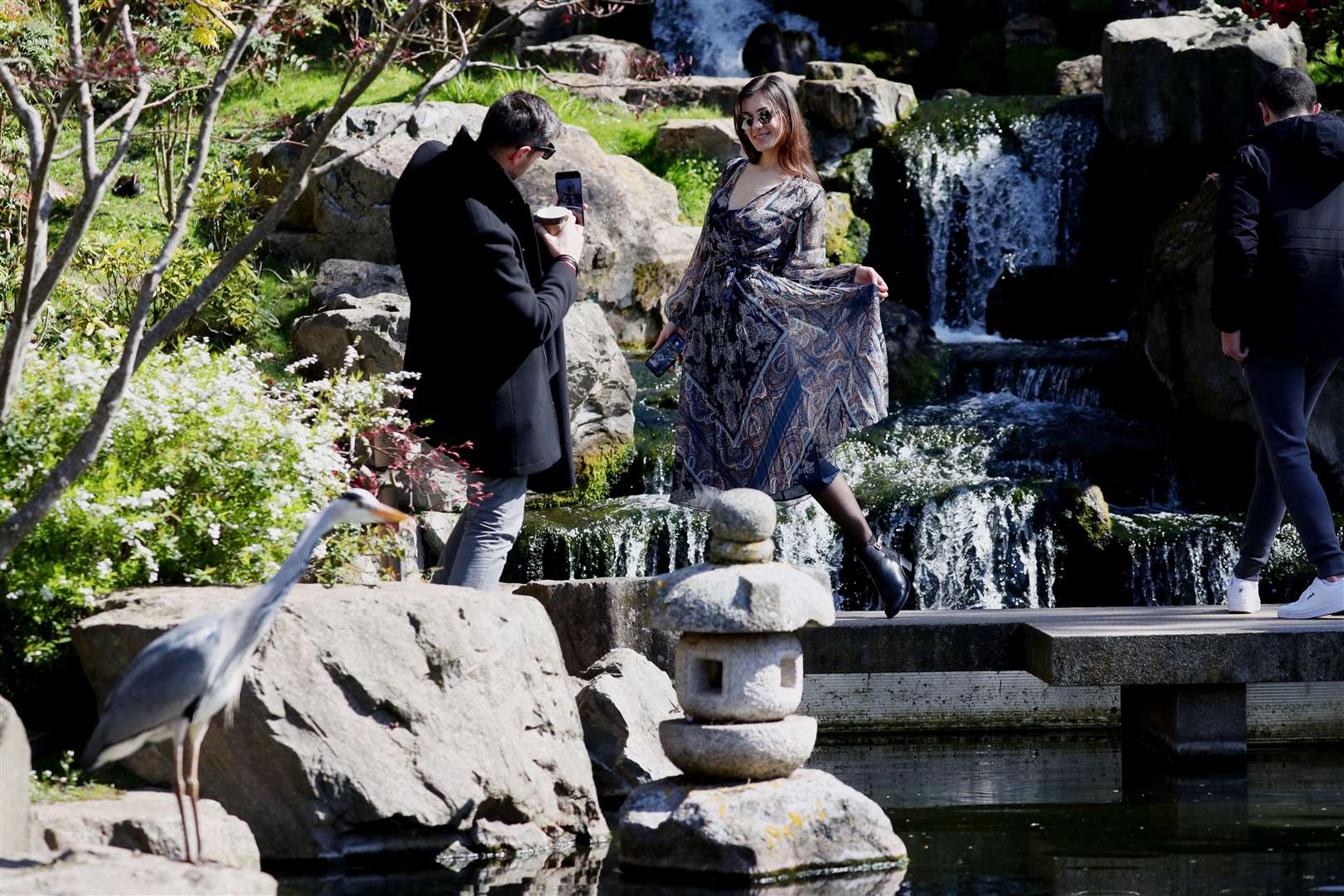 A woman poses beside a waterfall in the Kyoto Garden at Holland Park, London (Jonathan Brady/PA)