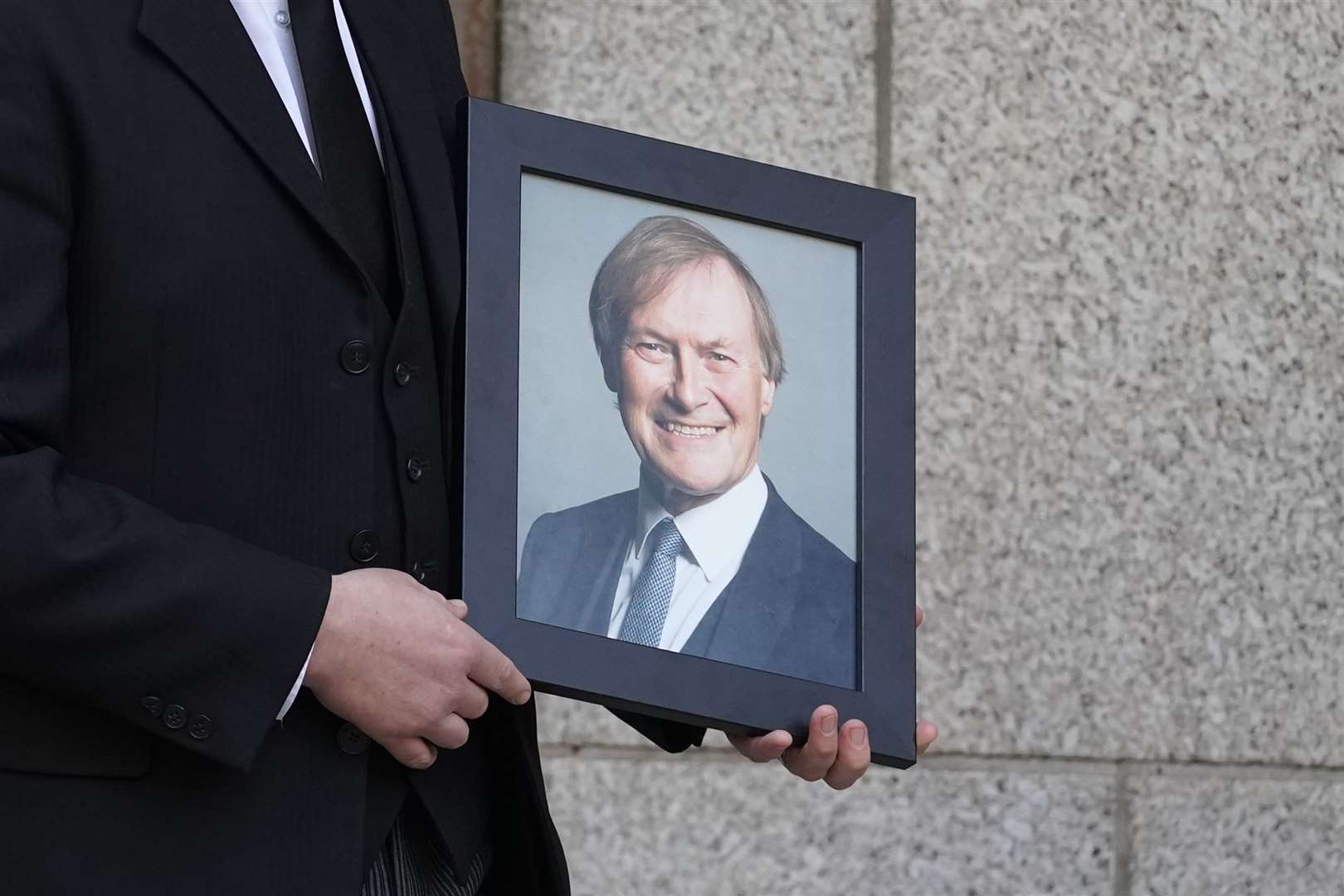 A photograph of Sir David Amess is held by a mourner (Kirsty O’Connor/PA)