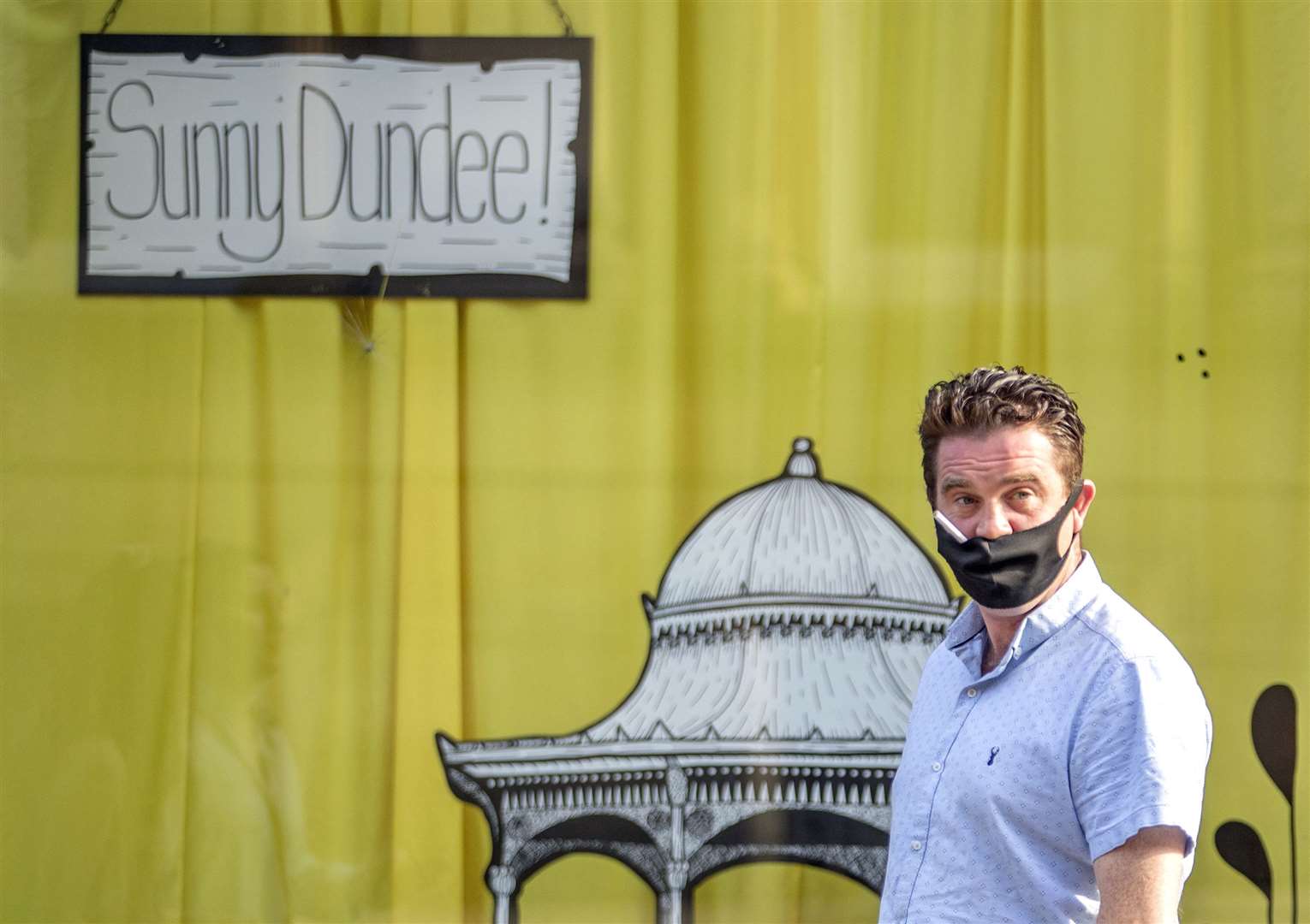 A man holds a cigarette in his mouth despite wearing a mask in Dundee (Jane Barlow/PA)