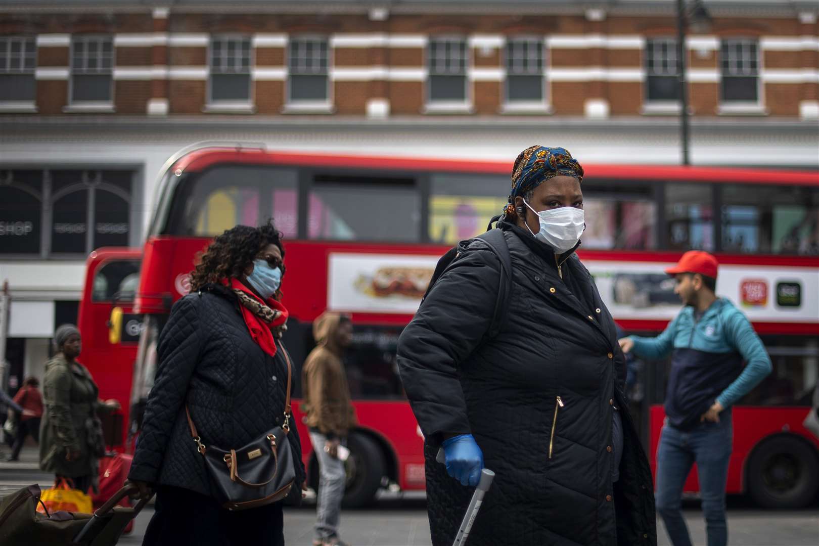 A woman in a protective face mask walks through Brixton Market in south London (Victoria Jones/PA)