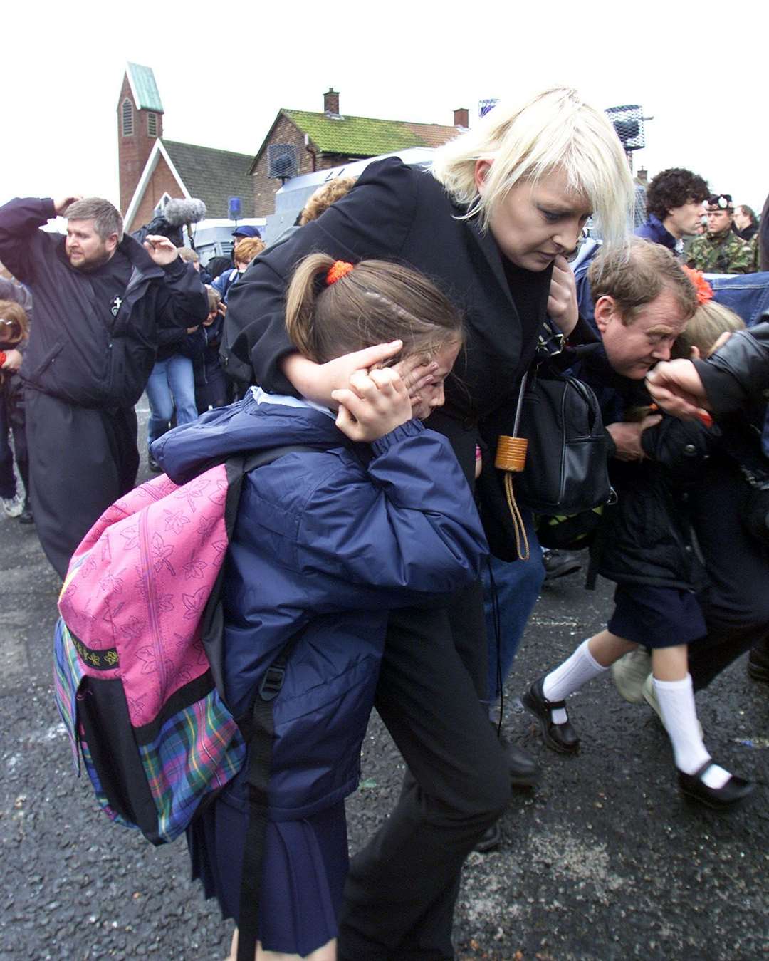 Children and parents run for cover along the Ardoyne Road in north Belfast, towards Holy Cross School (Paul Faith/PA)