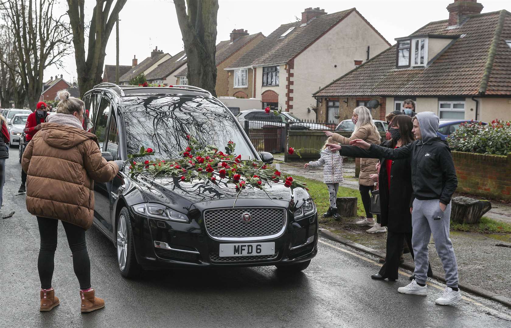 Members of the public place red roses on the hearse of Olly Stephens in February (Steve Parsons/PA)