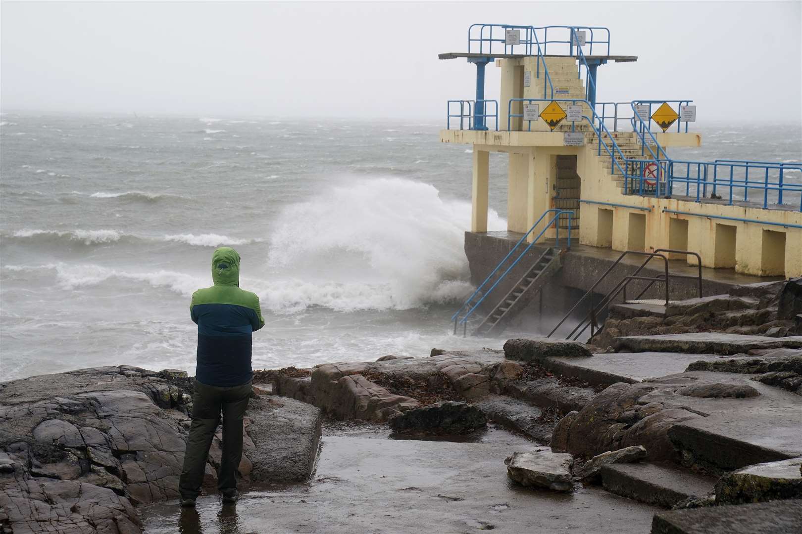 A person watches the waves in Salthill, Galway, as a Met Eireann orange alert came into effect at 10am for large parts of Ireland on Sunday (Brian Lawless/PA)