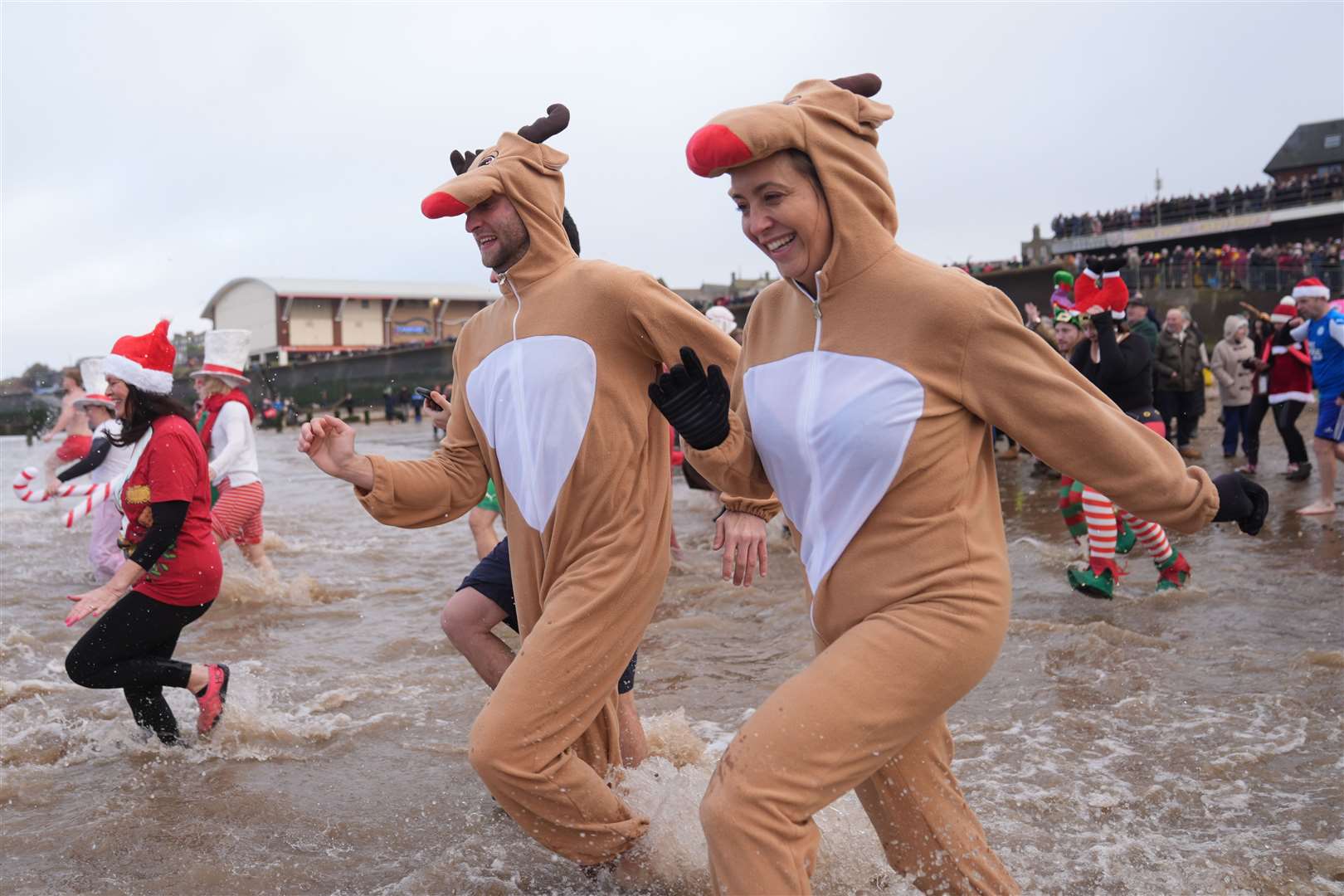 Dasher and Prancer, two swimmers in reindeer costumes run for the waves in Norfolk (Joe Giddens/PA)