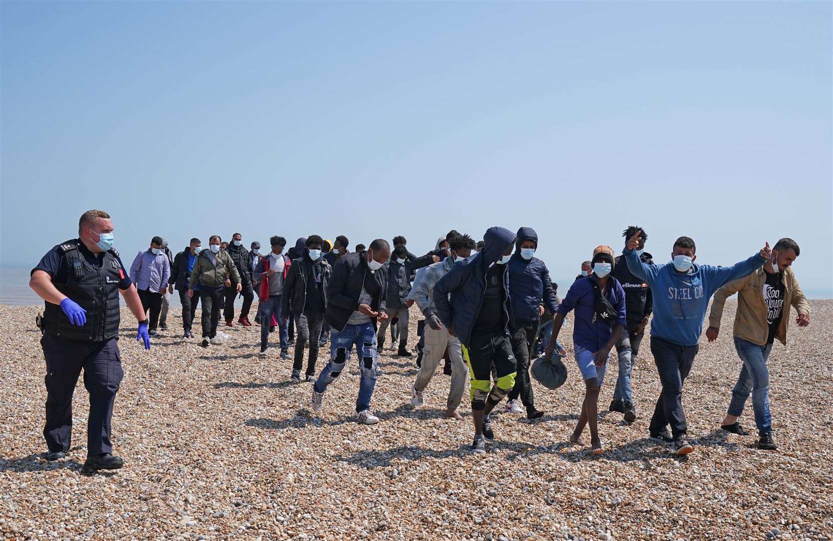 A group of people thought to be migrants are escorted from the beach in Dungeness (Gareth Fuller/PA)