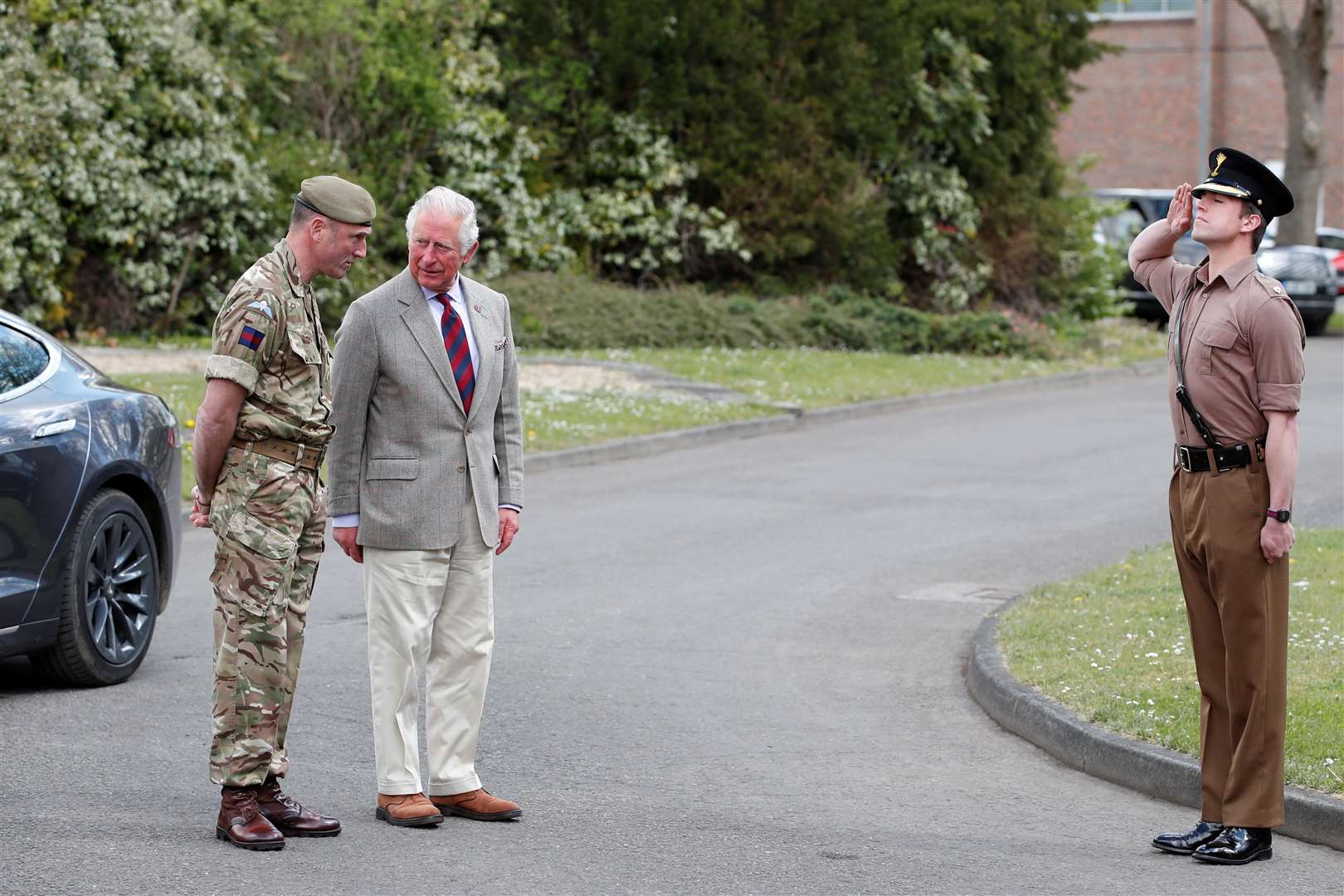 Charles, with his Tesla car in the background, is greeted by Lieutenant Colonel Henry Llewelyn-Usher, Commanding Officer of the 1st Battalion, Welsh Guards (Peter Cziborra/PA)