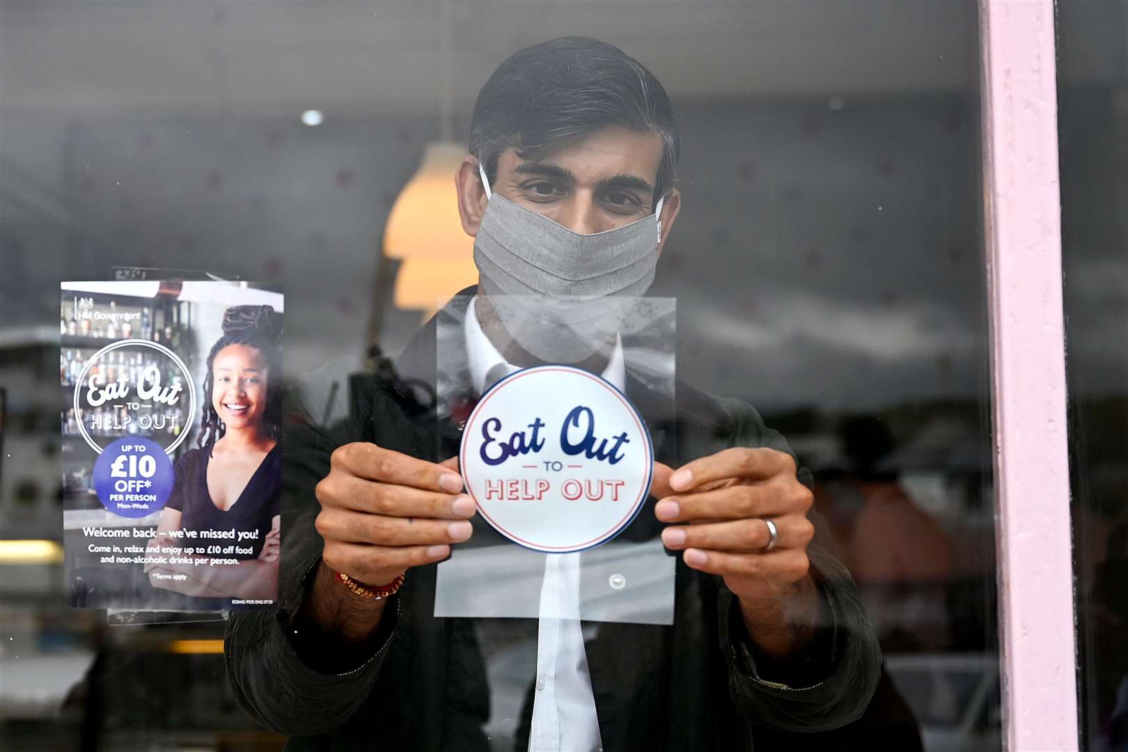 Chancellor of the Exchequer Rishi Sunak places an Eat Out to Help Out sticker in the window of a business (Jeff J Mitchell/PA)