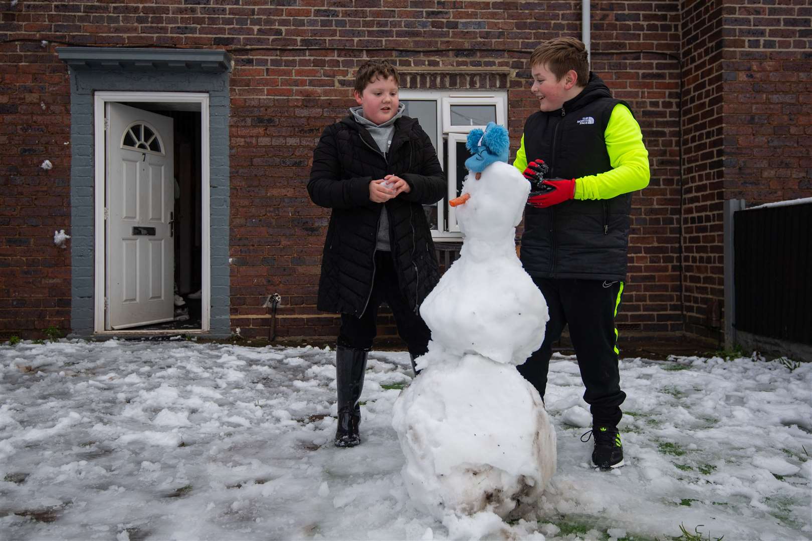 Brothers Max and Louis build a snowman outside their home in Stoke (Joe Giddens/PA)