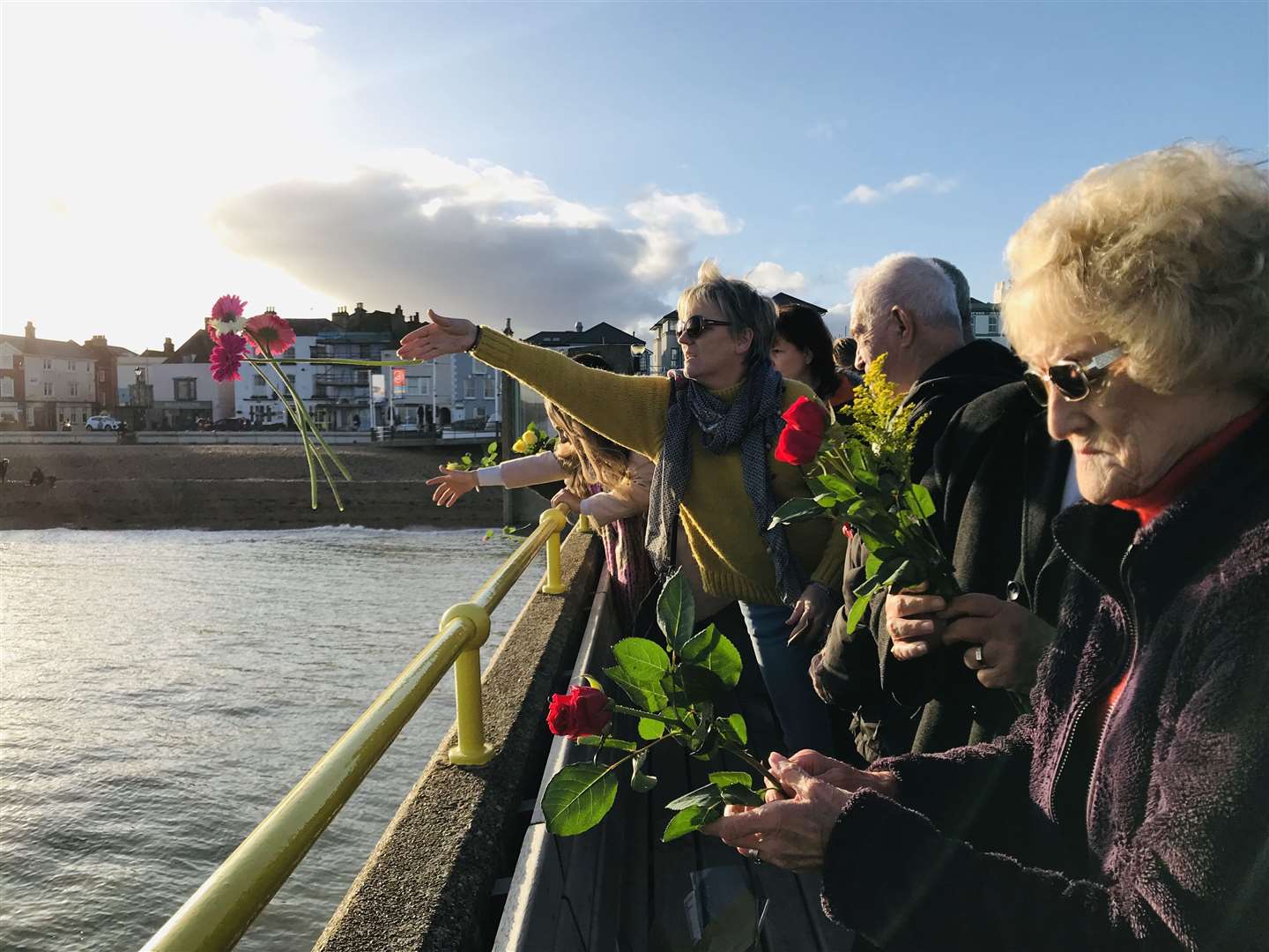 Debbie Grigg's cousin Terri Compson throws bright pink gerberas into the sea