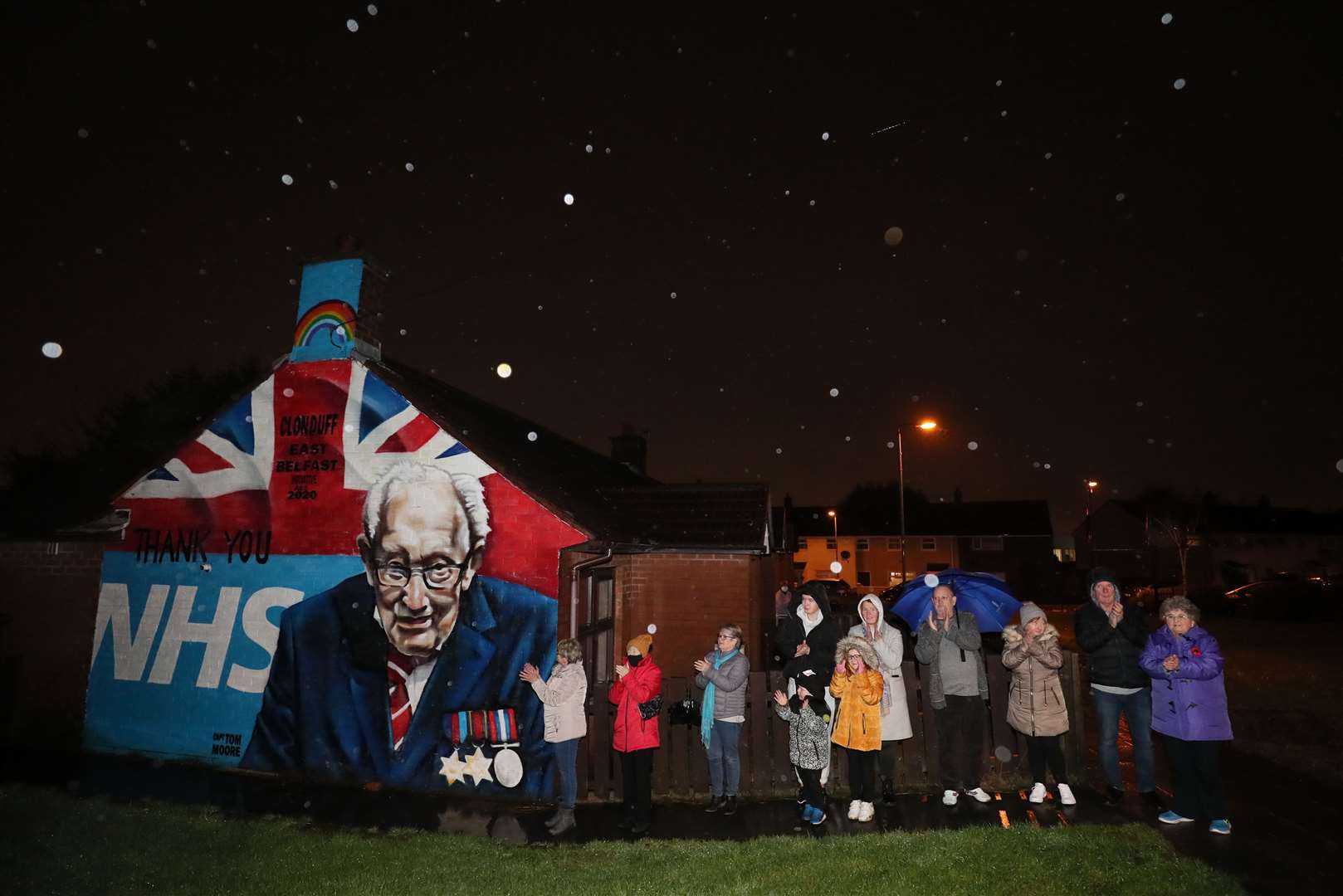 Local residents stand beside a mural of Captain Sir Tom Moore in Clonduff, east Belfast (Brian Lawless/PA)