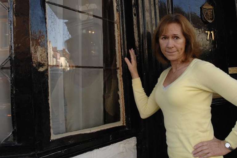 Sandie de Rougemont with the damaged window at the House of Agnes in Canterbury