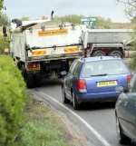 A lorry, trailed by a queue of cars, heads towards the fish farm