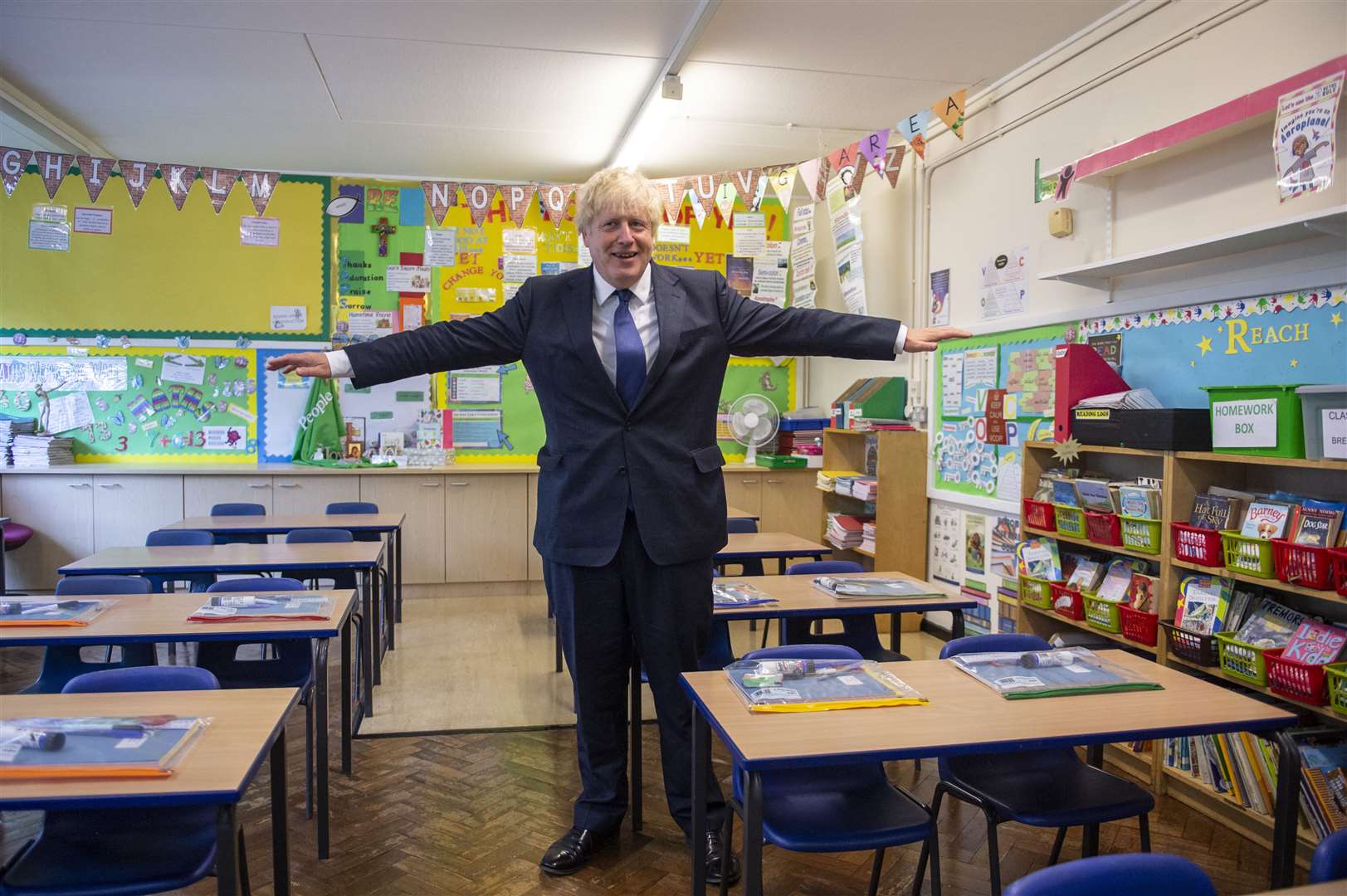 Prime Minister Boris Johnson holds his arms out, demonstrating the two-metre distancing rule, during a visit to a primary school in east London (Lucy Young/Evening Standard/PA)