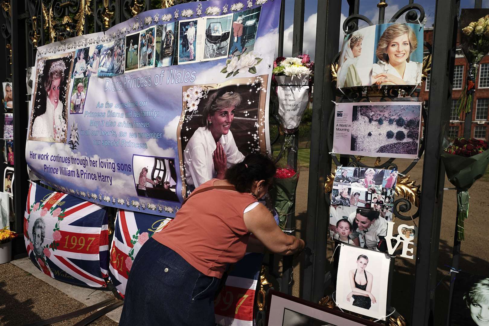 A person laying flowers on the gates outside Kensington Palace (Aaron Chown/PA)