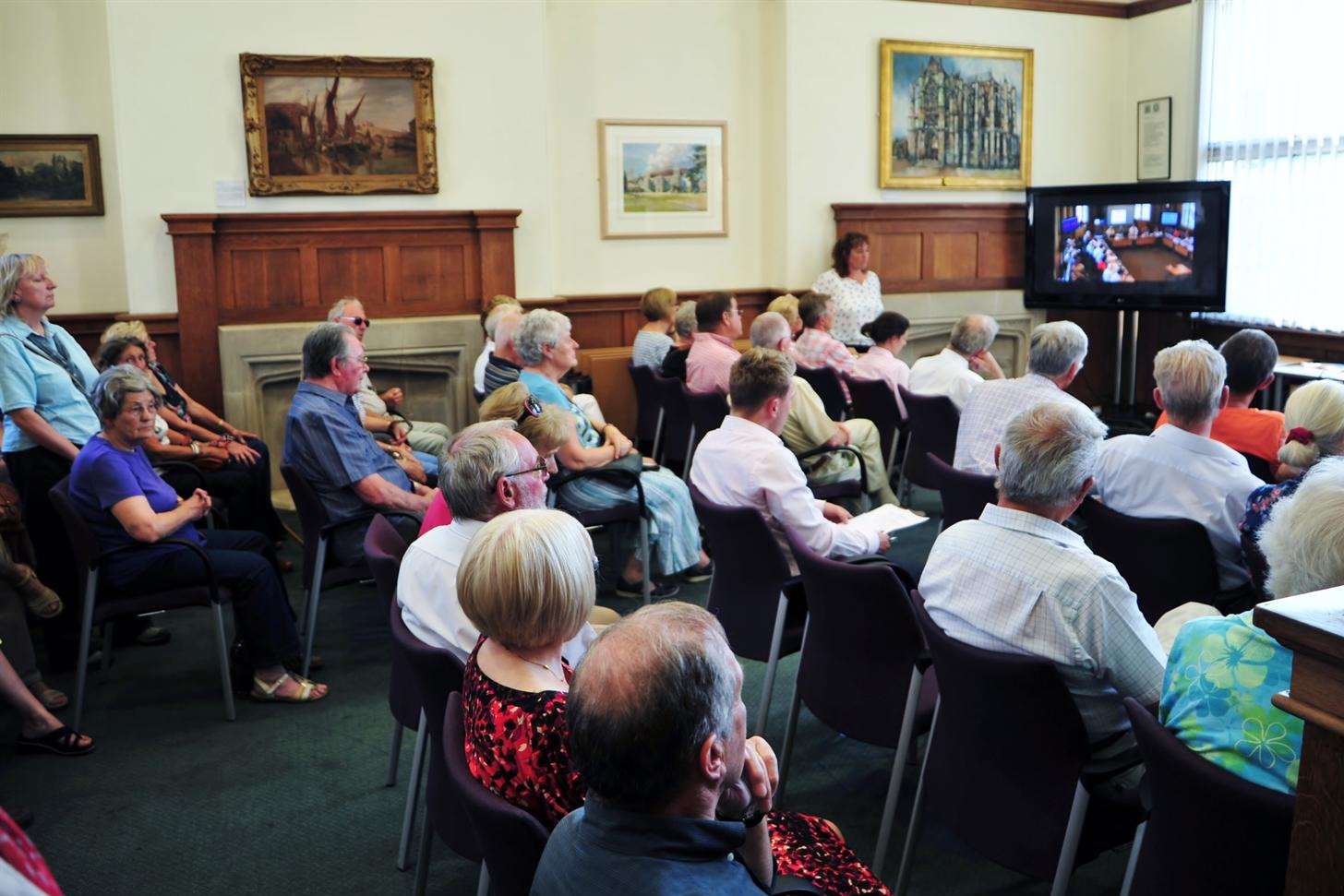 Members of the public watch the debate from an overflow chamber