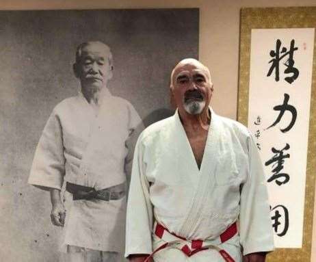 Trevor Davies in Japan in front of a photo of the founder of judo, Kano Jigoro