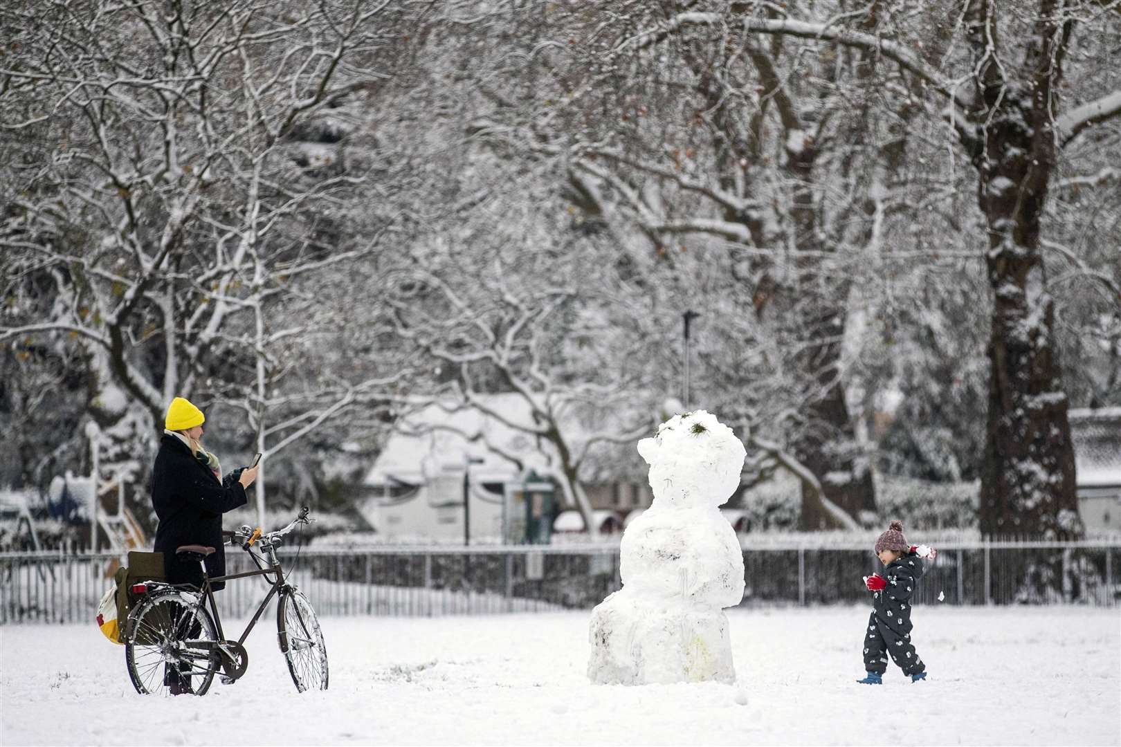 People beside a snowman in Kennington Park, London (Ben Whitley/PA)