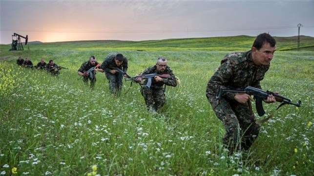 Mr Harrison, second from front, and fellow fighters walking through a field in Syria. Picture: bijikurdistan.tumblr.com