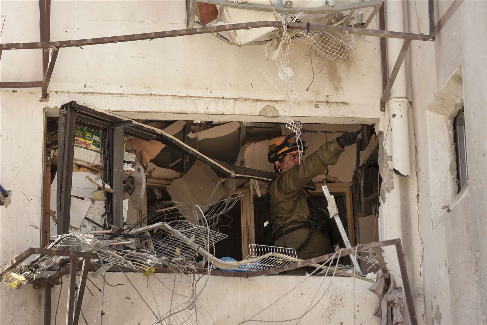 An Israeli soldier inspects damage to an apartment in a residential building after it was hit by a rocket fired from the Gaza Strip, in Ashdod, southern Israel (AP Photo/Maya Alleruzzo)