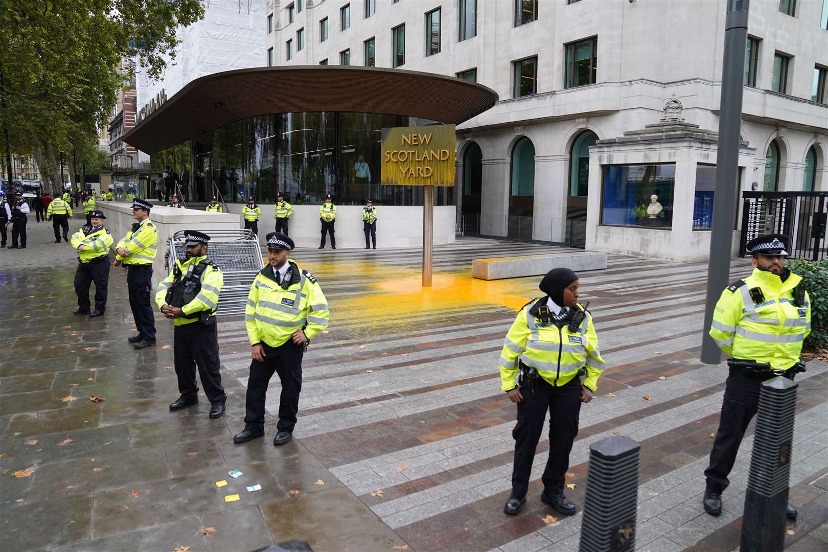 Police officers surround a sign which was spray painted by a Just Stop Oil protester outside New Scotland Yard in London (Stefan Rousseau/AP)