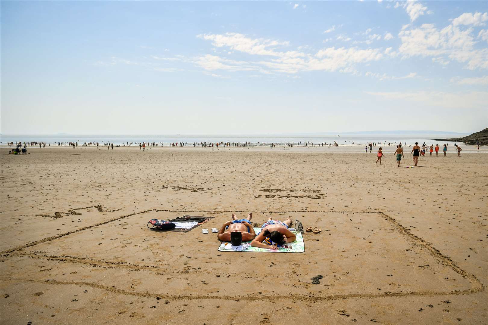 People sunbathe in a marked out square in the sand, indicating two metres, on Barry Island beach (Ben Birchall/PA)