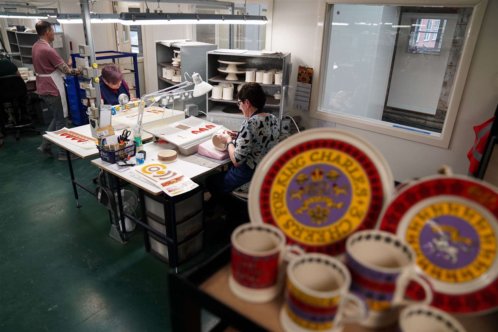 Pottery decorators add details to a crown and teapot during the production of hand-decorated pieces from the forthcoming coronation collection (Jacob King/PA)