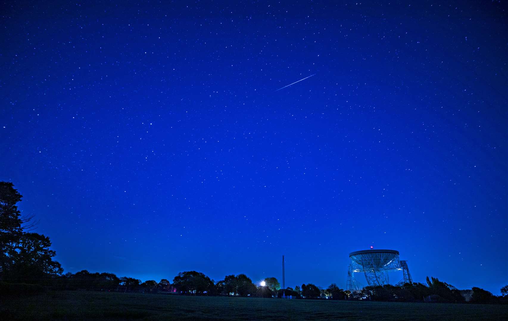 A Lyrid meteor passes over the Lovell telescope at Jodrell Bank in Macclesfield, Cheshire (Peter Byrne/PA)