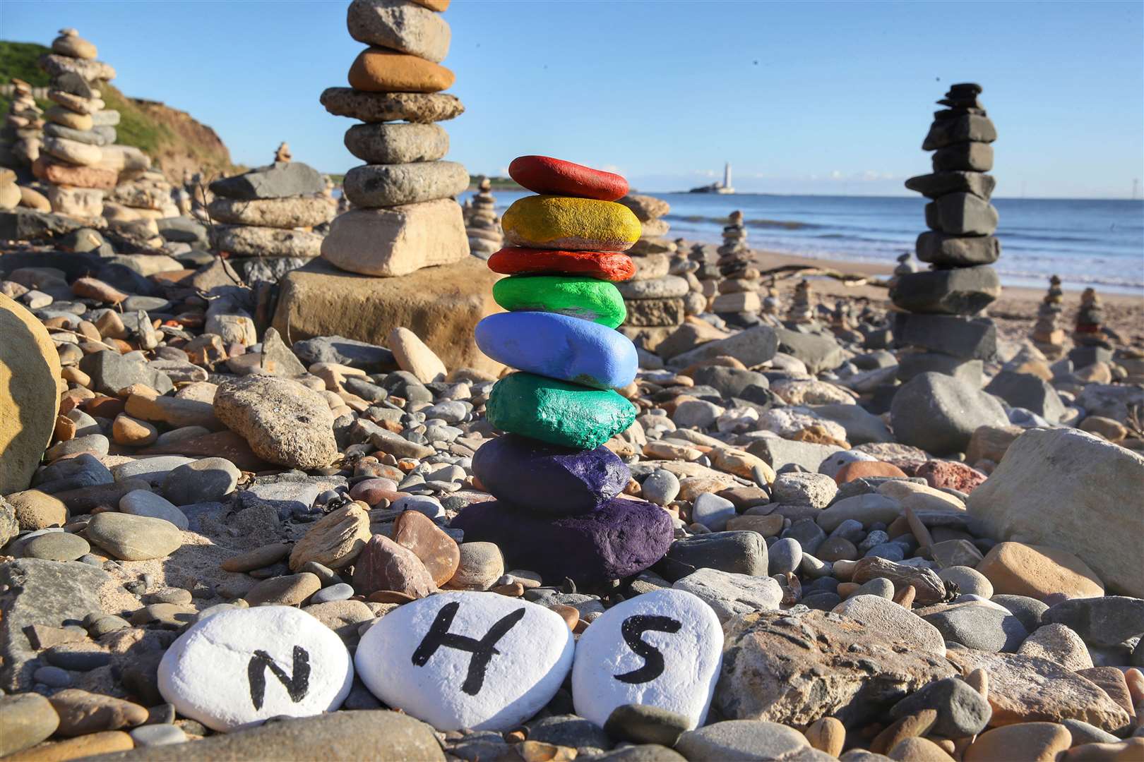 This pebble stack appeared on the beach at Whitley Bay – complete with a symbolic rainbow (Owen Humphreys/PA)