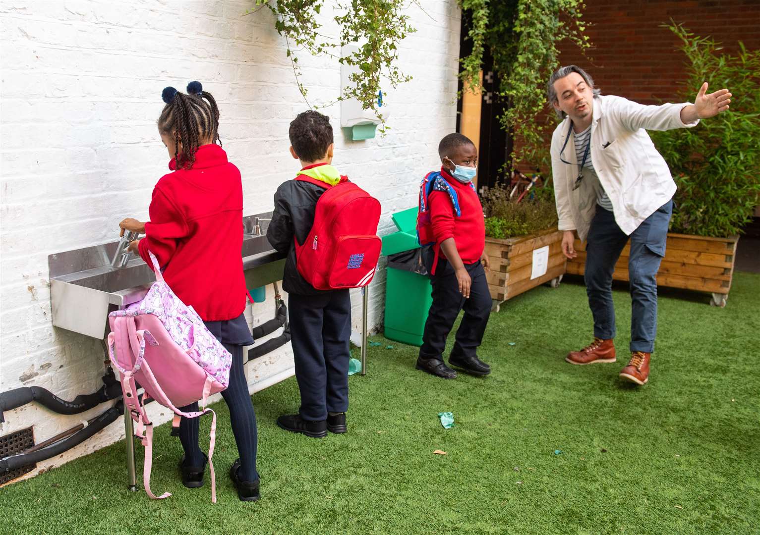 Pupils wash their hands as they arrive on the first day back at Charles Dickens Primary School (Dominic Lipinski/PA)