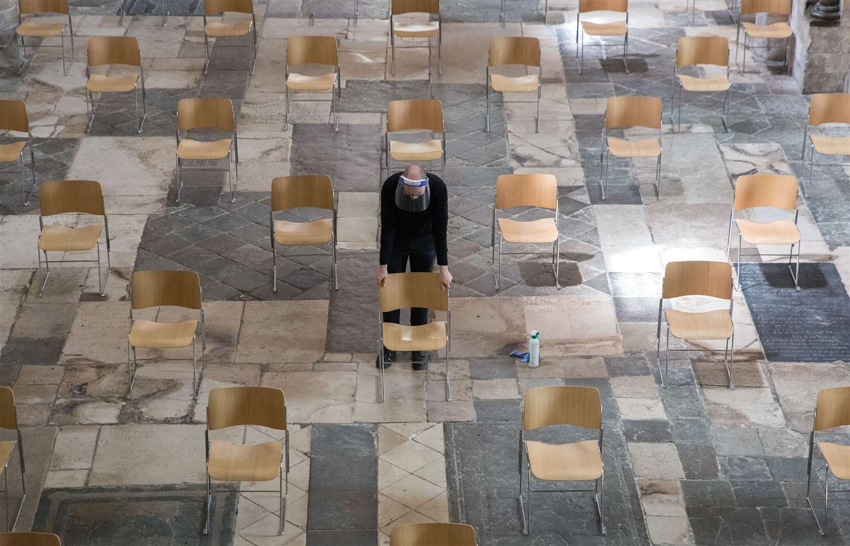 Senior Verger Luke Marshall moves a carefully spaced chair in to place in the nave of Chichester Cathedral in West Sussex (Andrew Matthews/PA)