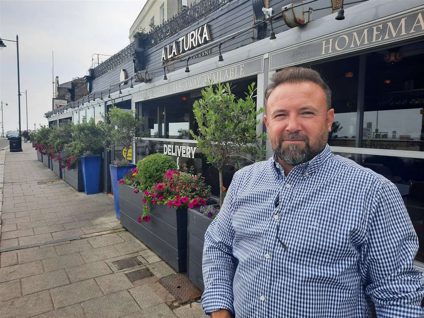 Mehmet Dari in front of the glass-panelled enclosure at A La Turka in Herne Bay